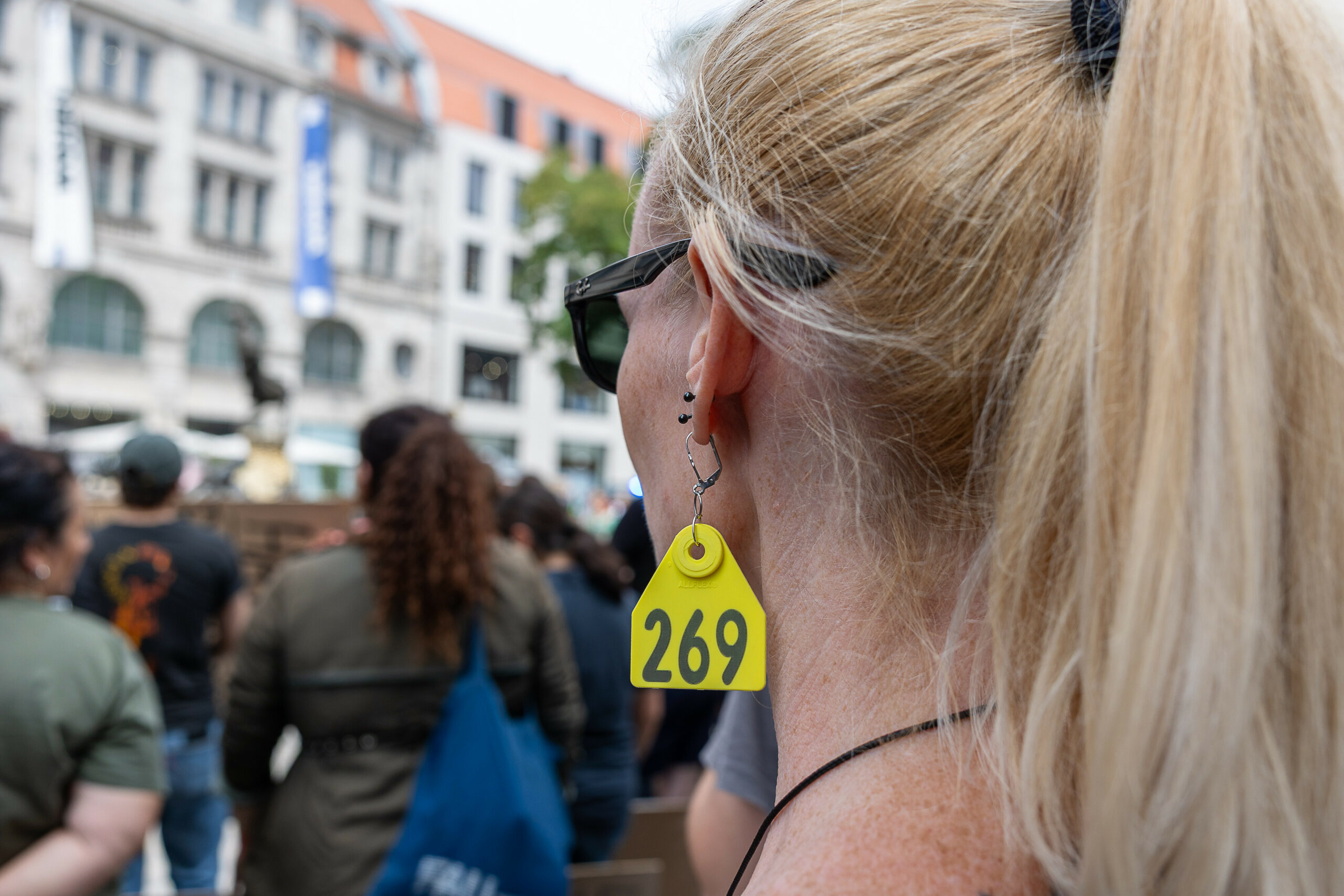 Teilnehmerin einer Tierschutz-Demo mit einer „269“-Ohrmarke als Schmuck.