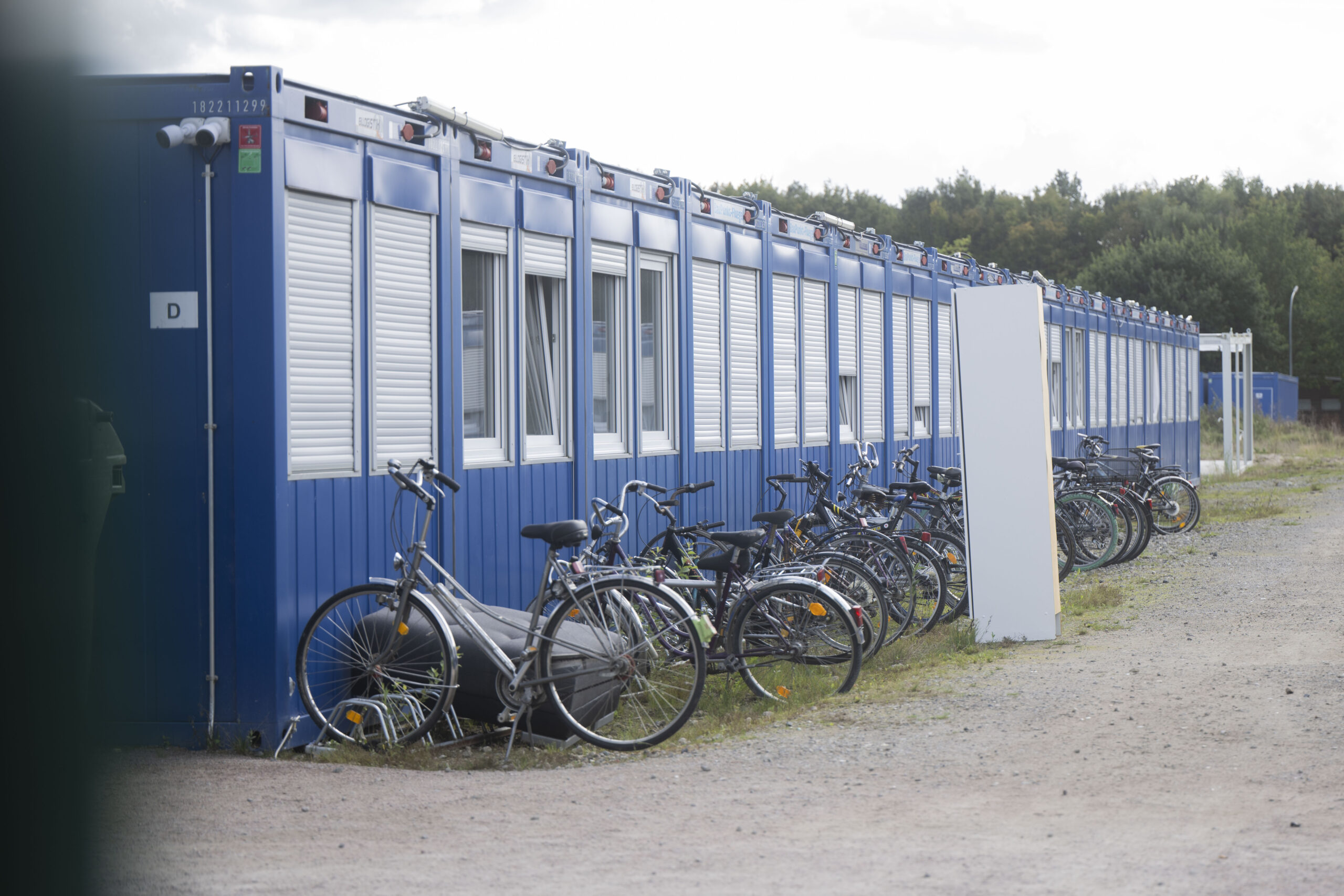Fahrräder und ein Möbelstück stehen vor Wohncontainern in der Flüchtlingsunterkunft.