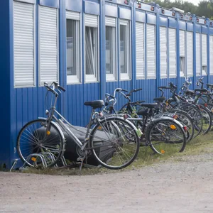 Fahrräder und ein Möbelstück stehen vor Wohncontainern in der Flüchtlingsunterkunft.