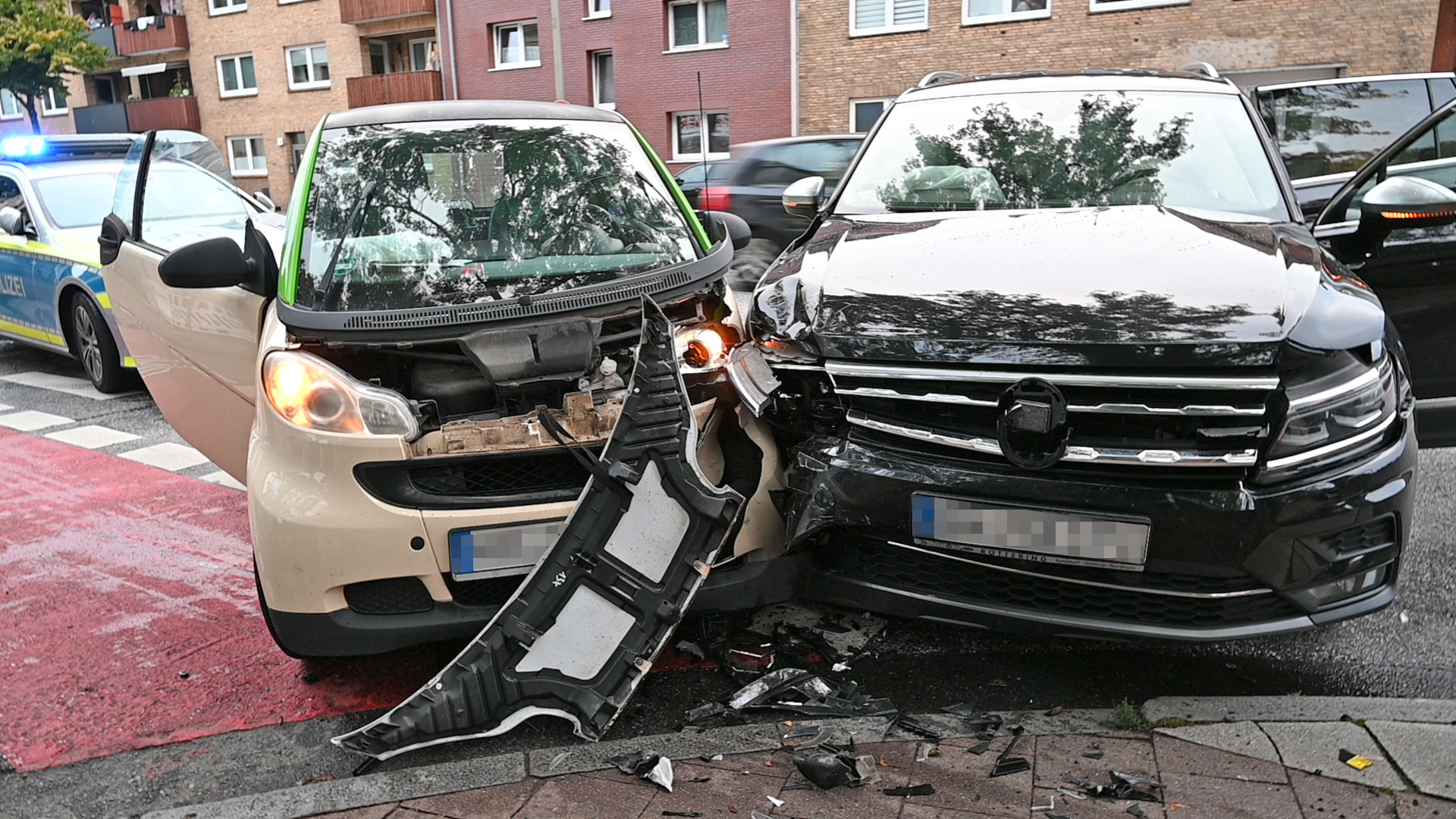 Zwei Autos stehen am Straßenrand. Die Fahrzeugfronten sind an der einen Seite aneinander gedrüclkt. Beide Fahrzeuge sind stark beschädigt.