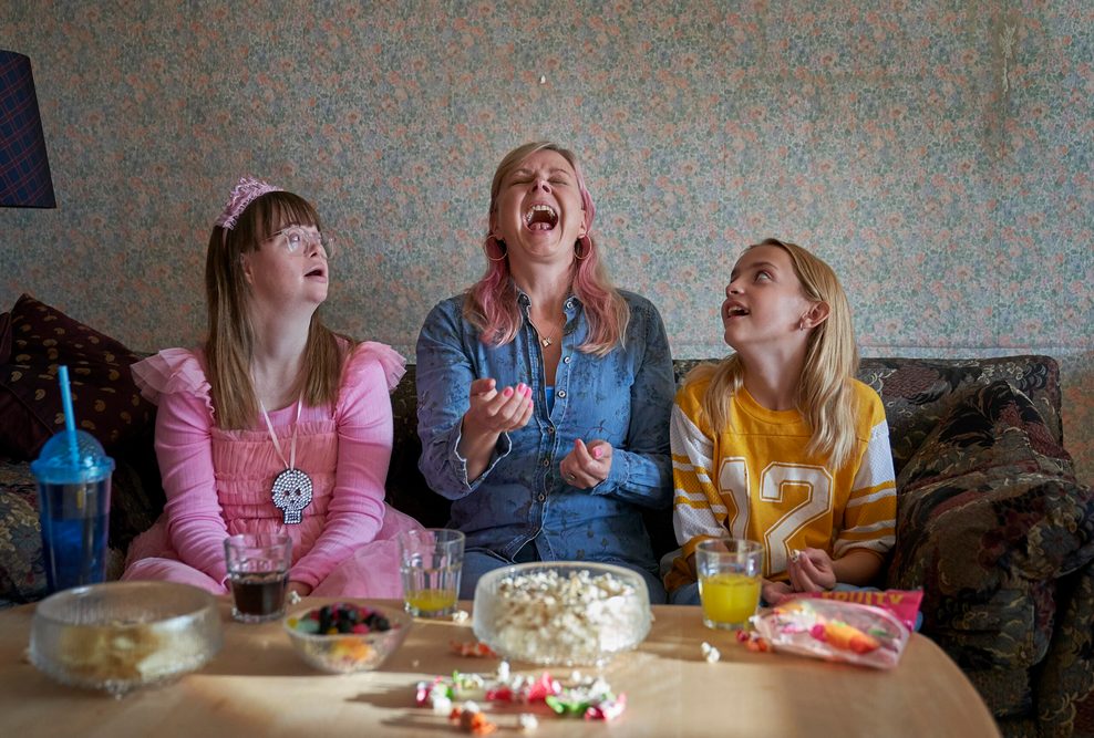 Eine Frau und zwei Mädchen sitzen auf einem Sofa.