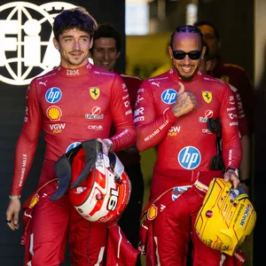 Lewis Hamilton neben Charles Leclerc, beide in Rennkleidung und mit Helm in der Hand.