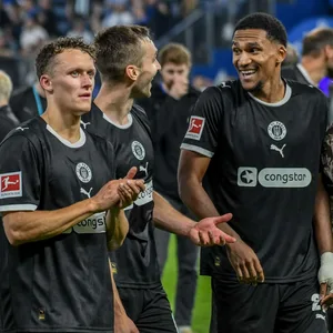 Martijn Kaars, James Sands und Andréas Hountondji stehen vor der Fankurve
