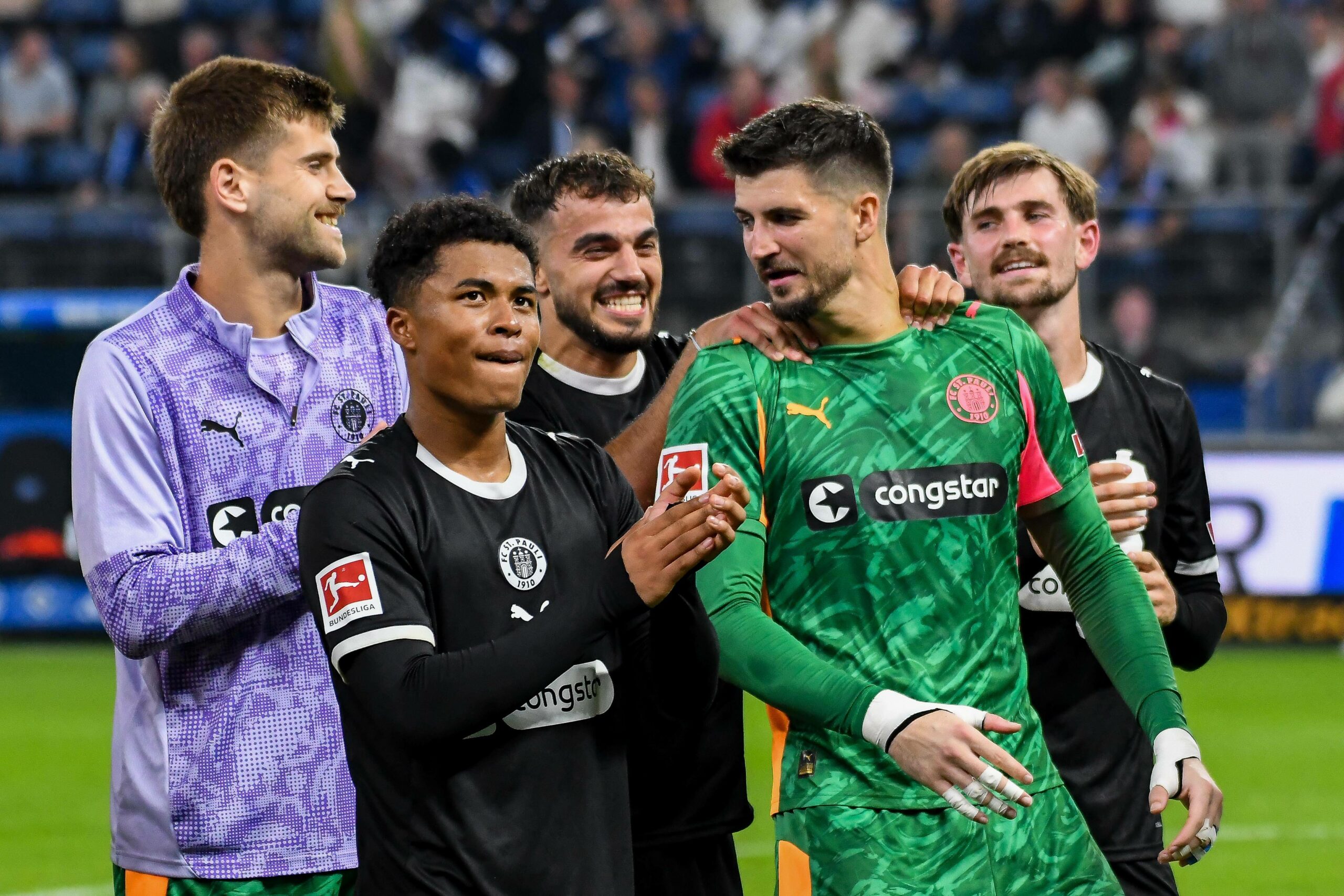 Ben Voll, Joel Chima Fujita, Danel Sinani, Nikola Vasilj und Connor Metcalfe freuen sich vor der Fankurve
