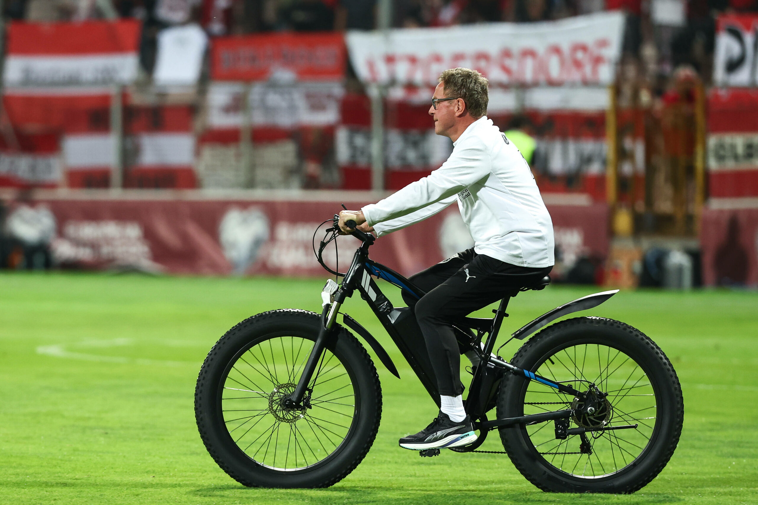 Rangnick mit E-Bike auf Stadionrasen.