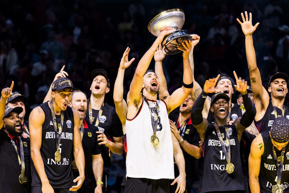 Deutschlands Basketballer beim Feiern des EM-Siegs. Franz Wagner trägt das Trikot seines Bruders und reckt die Trophäe in die Höhe.