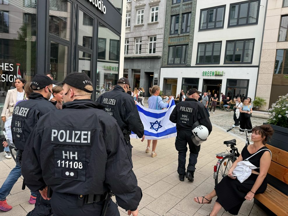 Polizeibeamte führen zwei Frauen mit Israel-Flagge weg von der Demonstration.