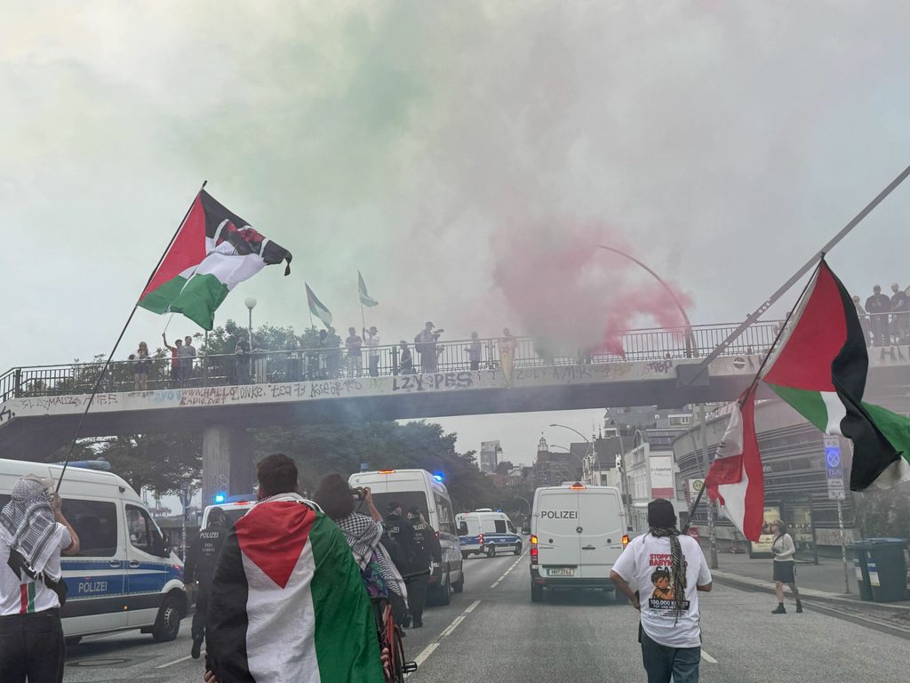 An den Landungsbrücken legt sich grün-roter Rauch über die Demonstration.