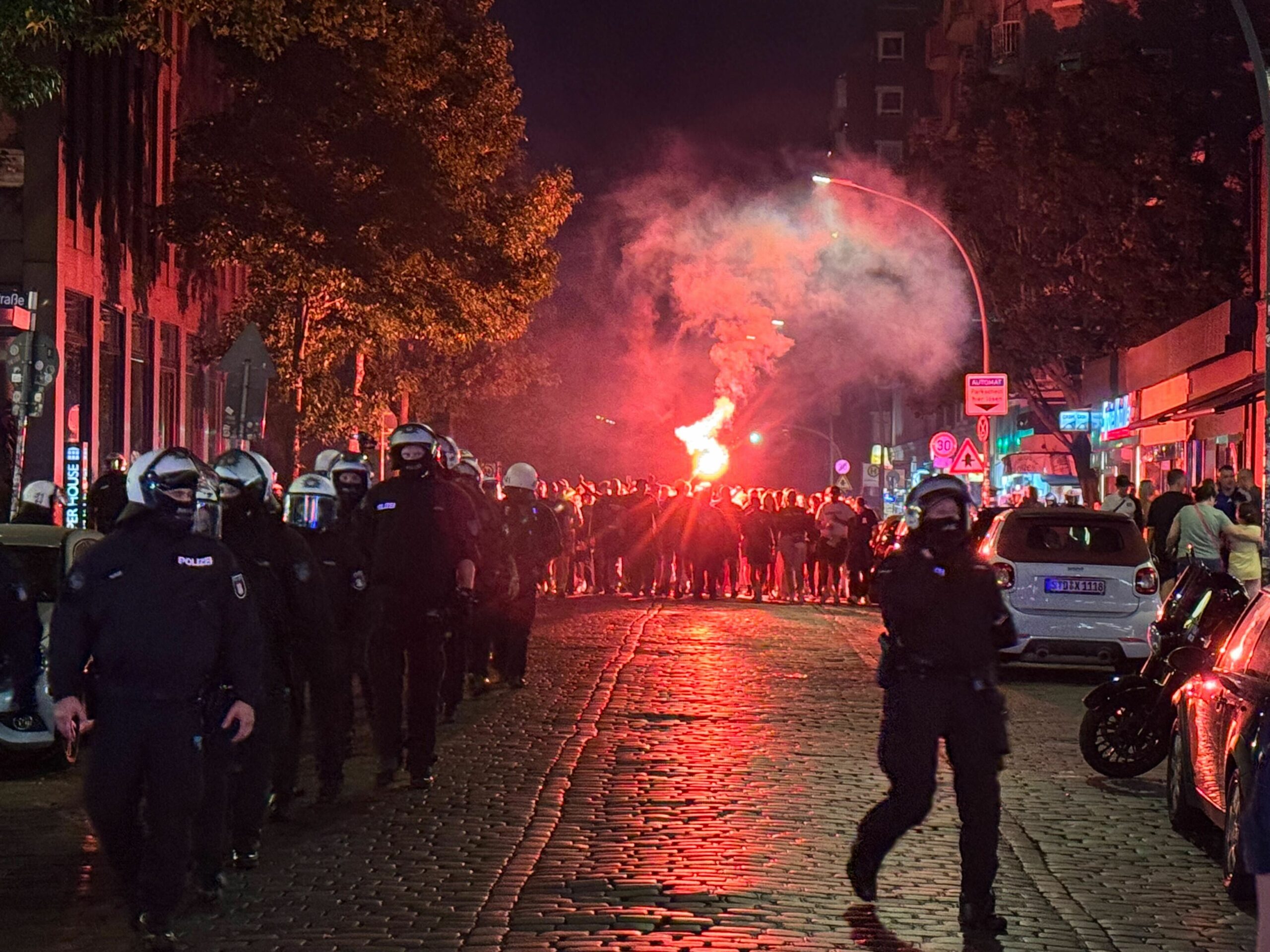 Polizei mit Pyrotechnik im Hintergrund