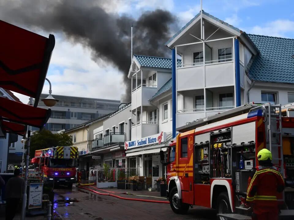 Dunkler Rauch steigt über einem Haus in den Himmel.