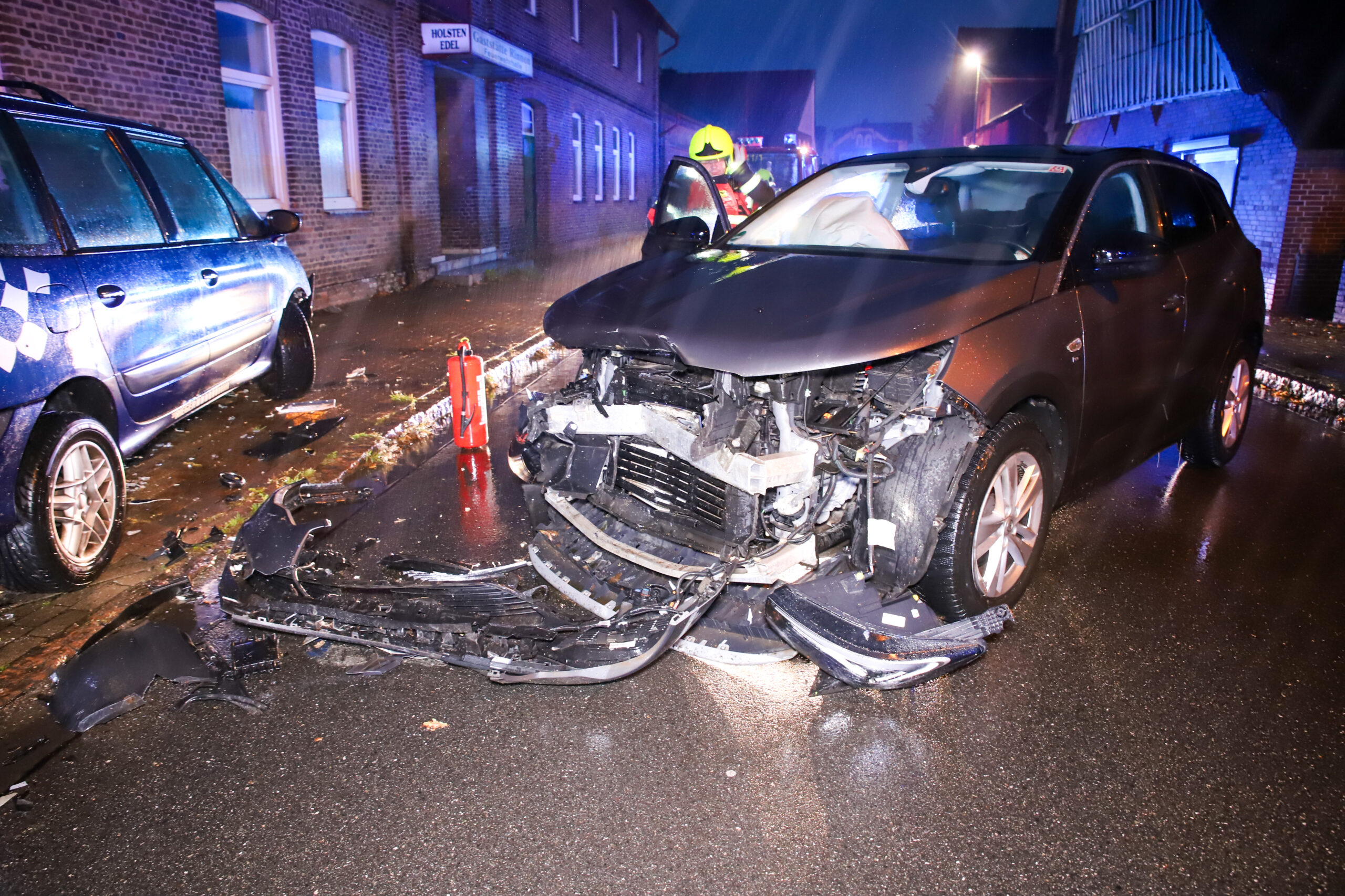 Ein Auto mit zerstörter Frontseite steht bei Regen auf der Straße.