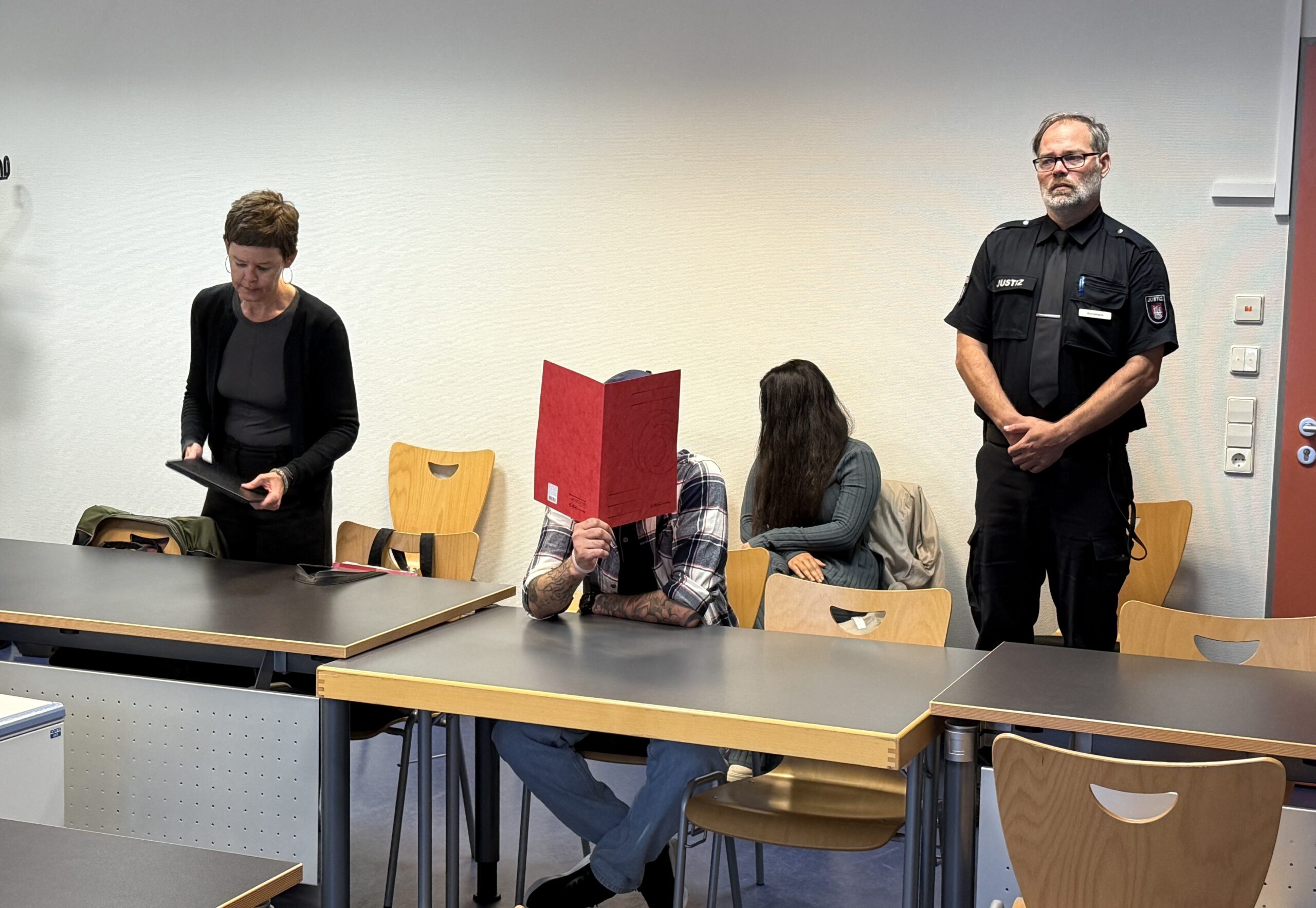 Der Angeklagte Mohanad G. sitzt mit einer roten Mappe vor dem Gesicht in Saal 1.07 des Amtsgerichtes St. Georg.