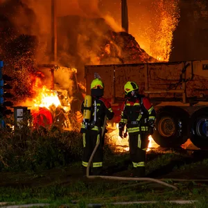 Einsatzkräfte vor der brennenden Lagerhalle.