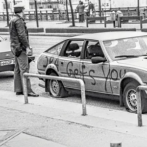 Der beschmierte und demolierte Rover des britischen Offiziers steht an der St. Pauli Hafenstraße. Ein Polizist bewacht das Fahrzeug.
