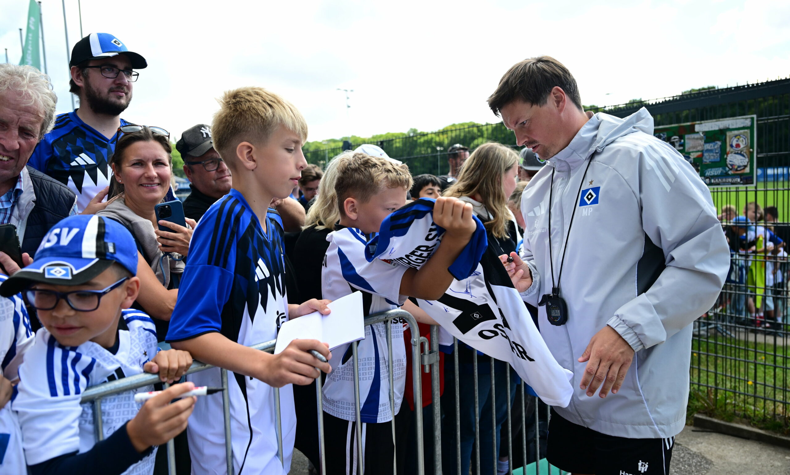 Trainer Merlin Polzin unterschreibt für einen Fan auf dem neuen HSV-Heimtrikot.