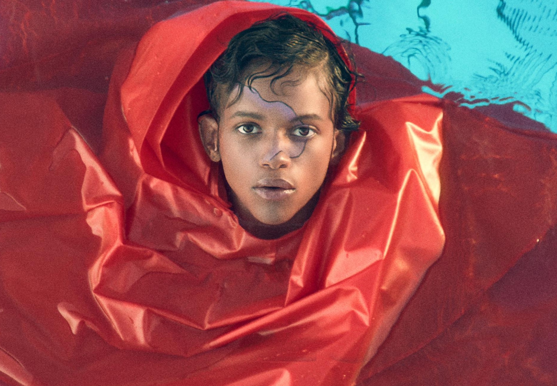 Sie treibt Wasser, man sieht nur ihr Gesicht, der Rest ist von roter Folie bedeckt