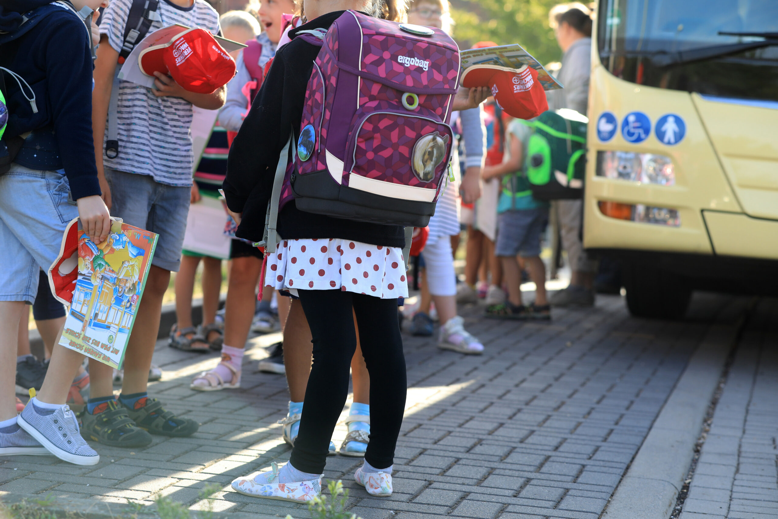 Kinder stehen mit ihrem Ranzen vor einem Schulbus (Symbolfoto).