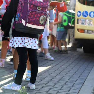 Kinder stehen mit ihrem Ranzen vor einem Schulbus (Symbolfoto).