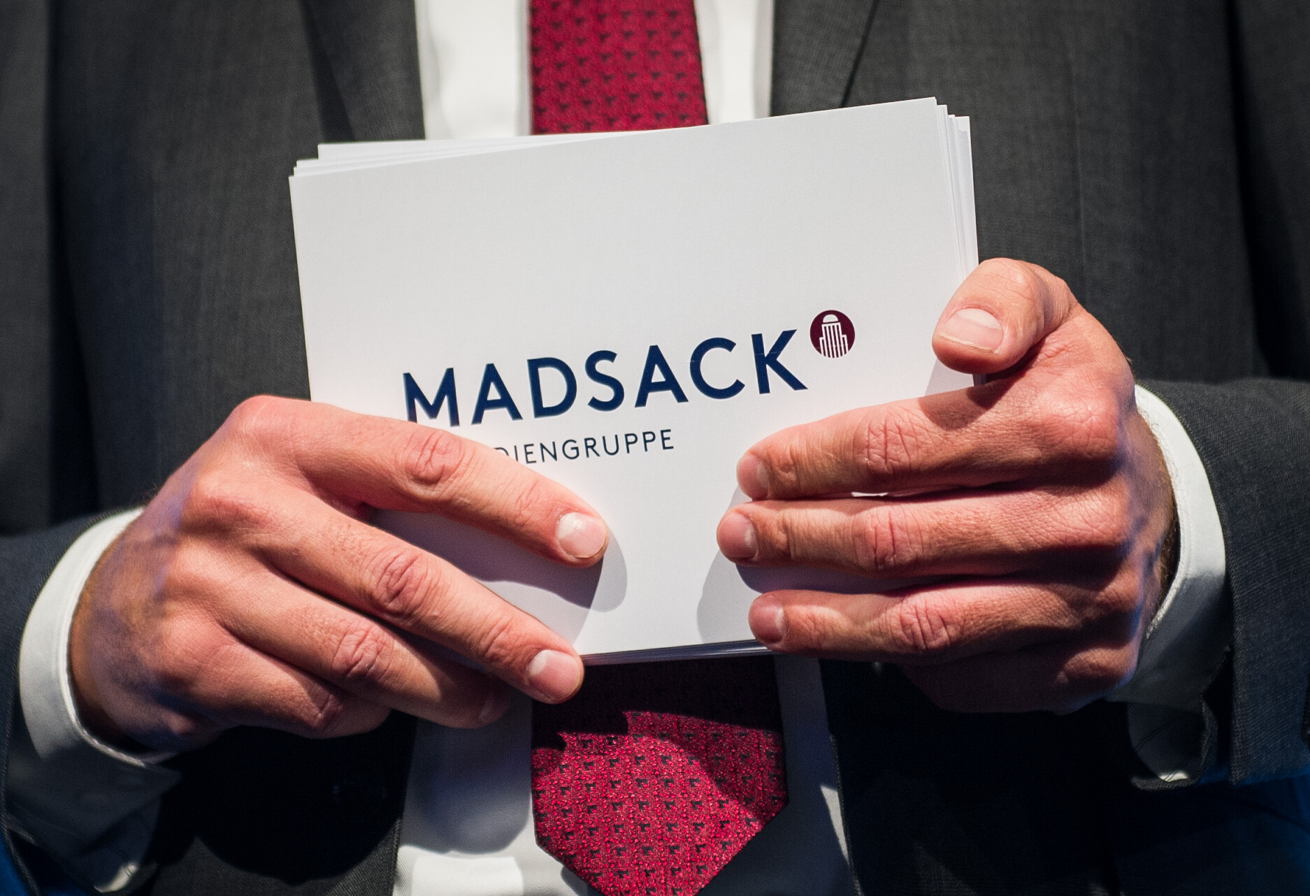 Hände halten eine Karte mit der Aufschrift Madsack.