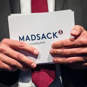 Hände halten eine Karte mit der Aufschrift Madsack.