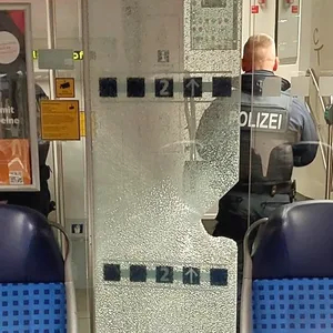 Ein Bundespolizist steht vor einer beschädigten Glastür in einer Regionalbahn.