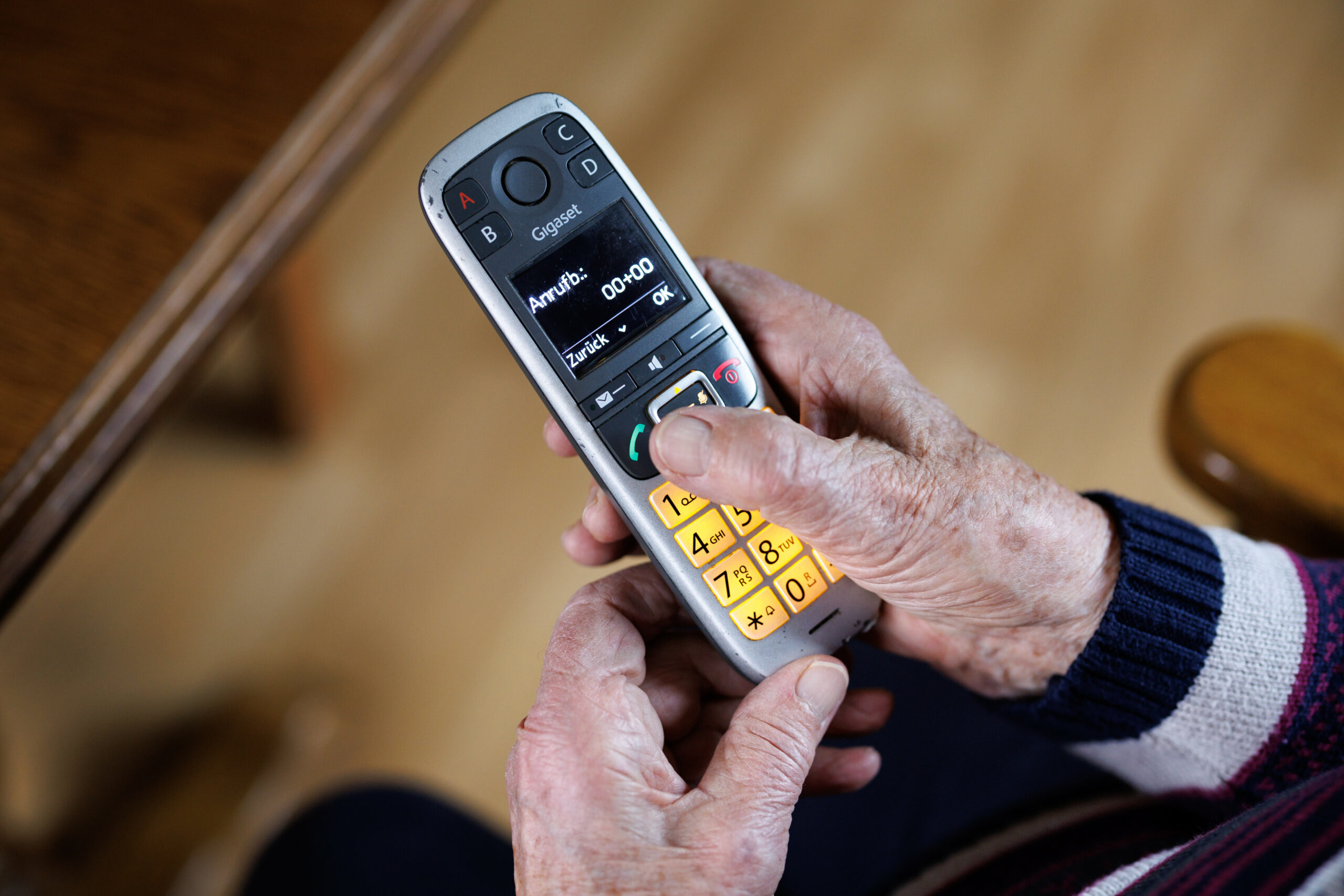 Ältere Person mit Festnetz-Telefon in den Händen.