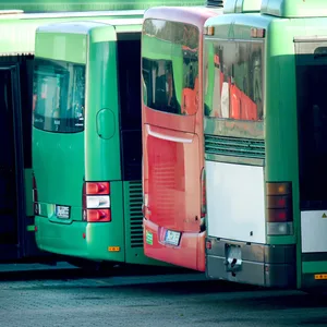 Ein Busdepot mit mehreren parkenden Bussen. Ein Fahrer läuft im Vordergrund.