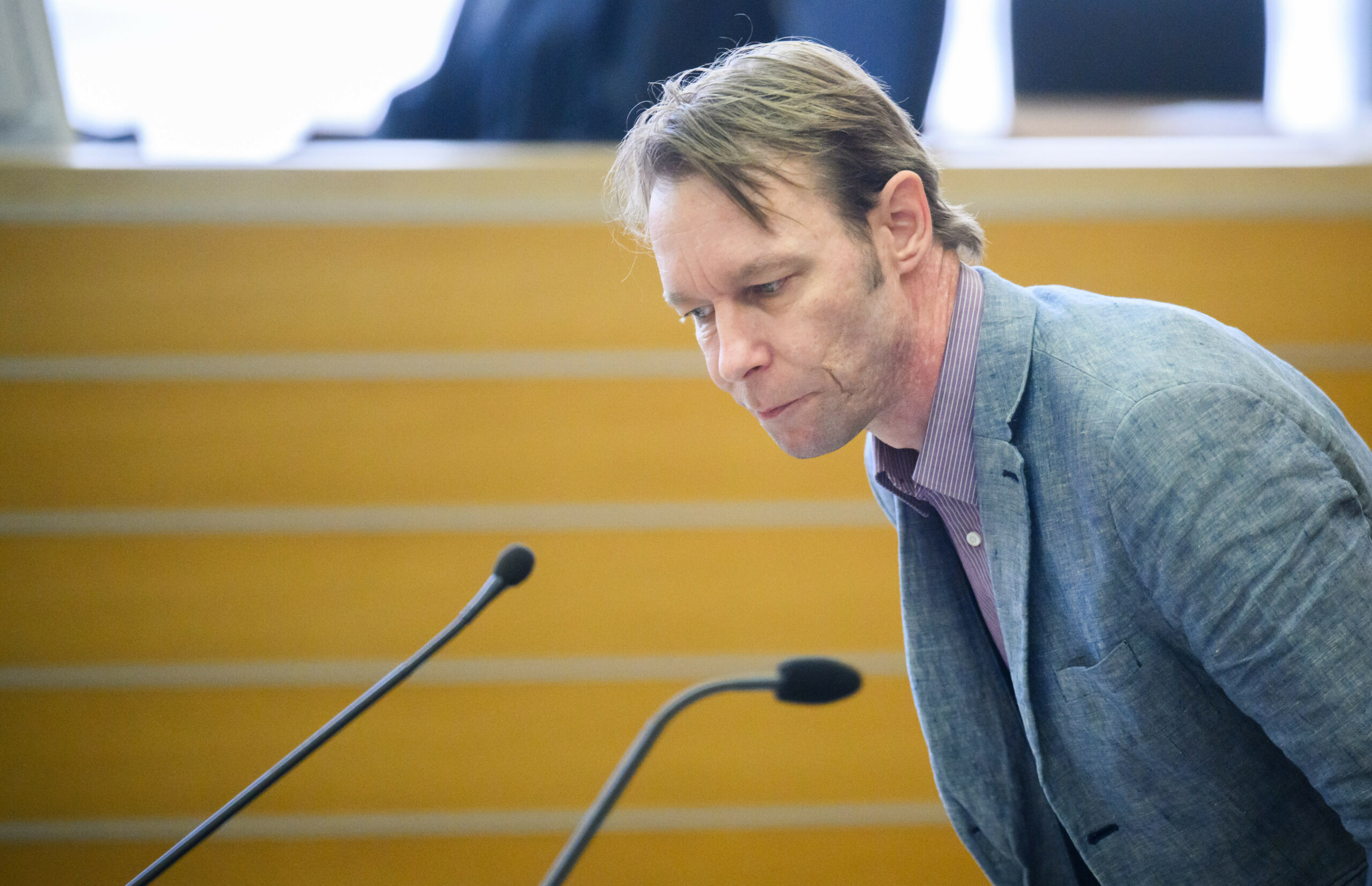 Mann in grauem Anzug vor Mikrofonen