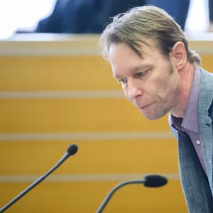 Mann in grauem Anzug vor Mikrofonen