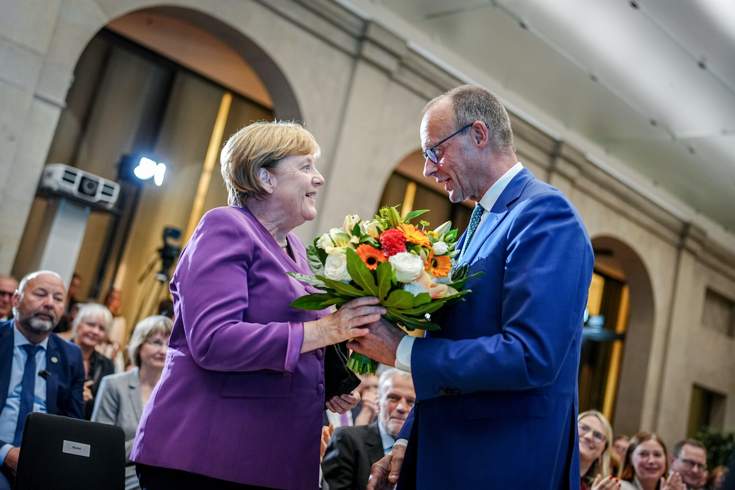 Friedrich Merz überreicht Angela Merkel beim Berliner Gespräch Spezial zum 70. Geburtstag der früheren Bundeskanzlerin einen Blumenstrauß.