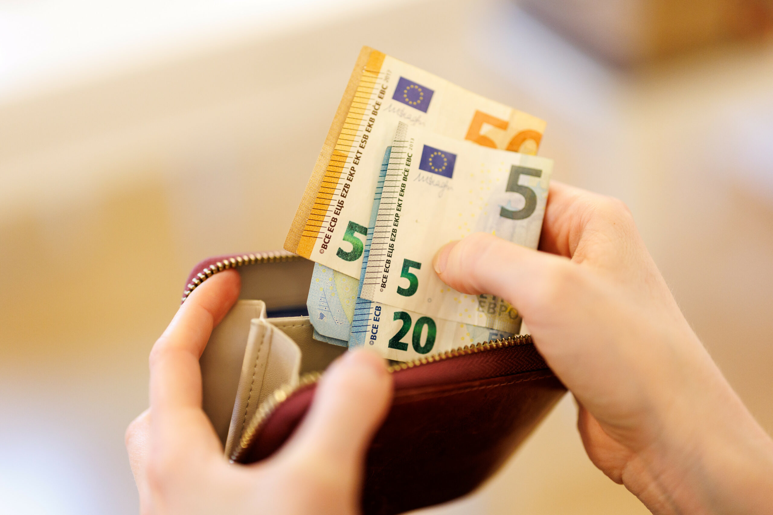 Hände die Geldscheine in ein Portemonnaie reintun.