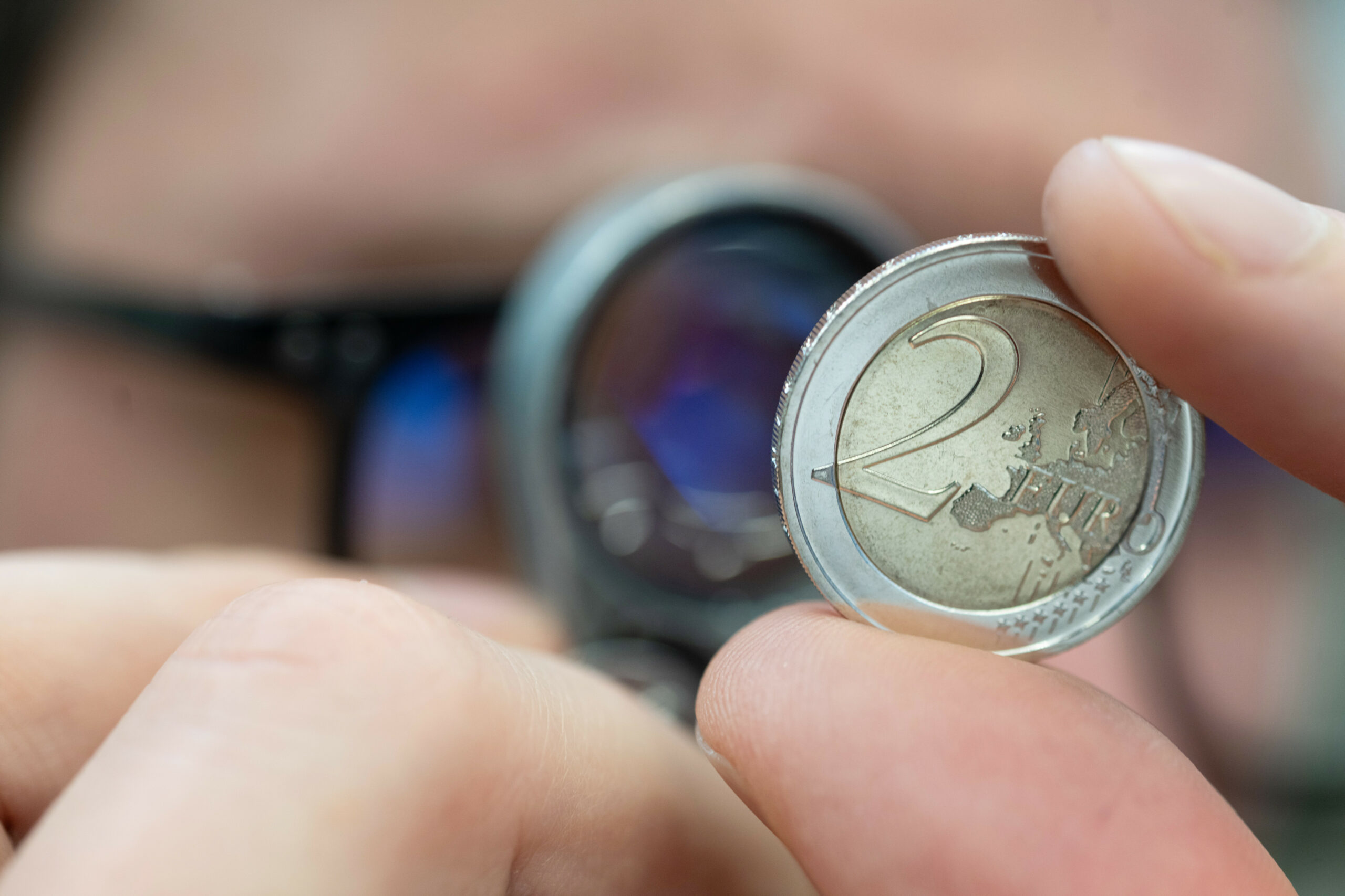 Gutachter führt eine Sichtkontrolle an einer Zwei-Euro-Münze durch. (Symbolbild)