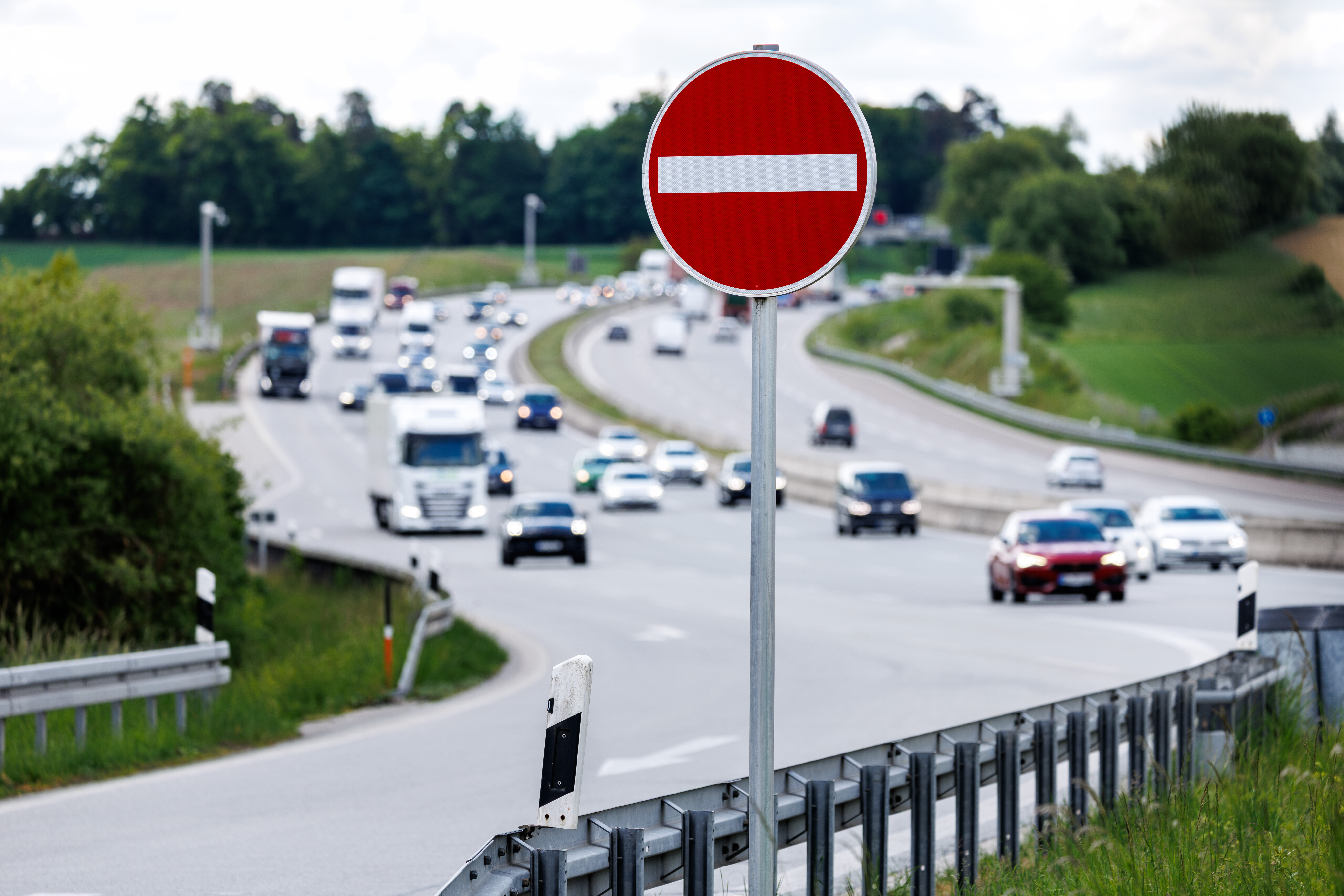 Das Verbotsschild ”Einfahrt verboten” an einer Autobahnausfahrt. Dahinter verschwommenAutos auf der Autobahn.