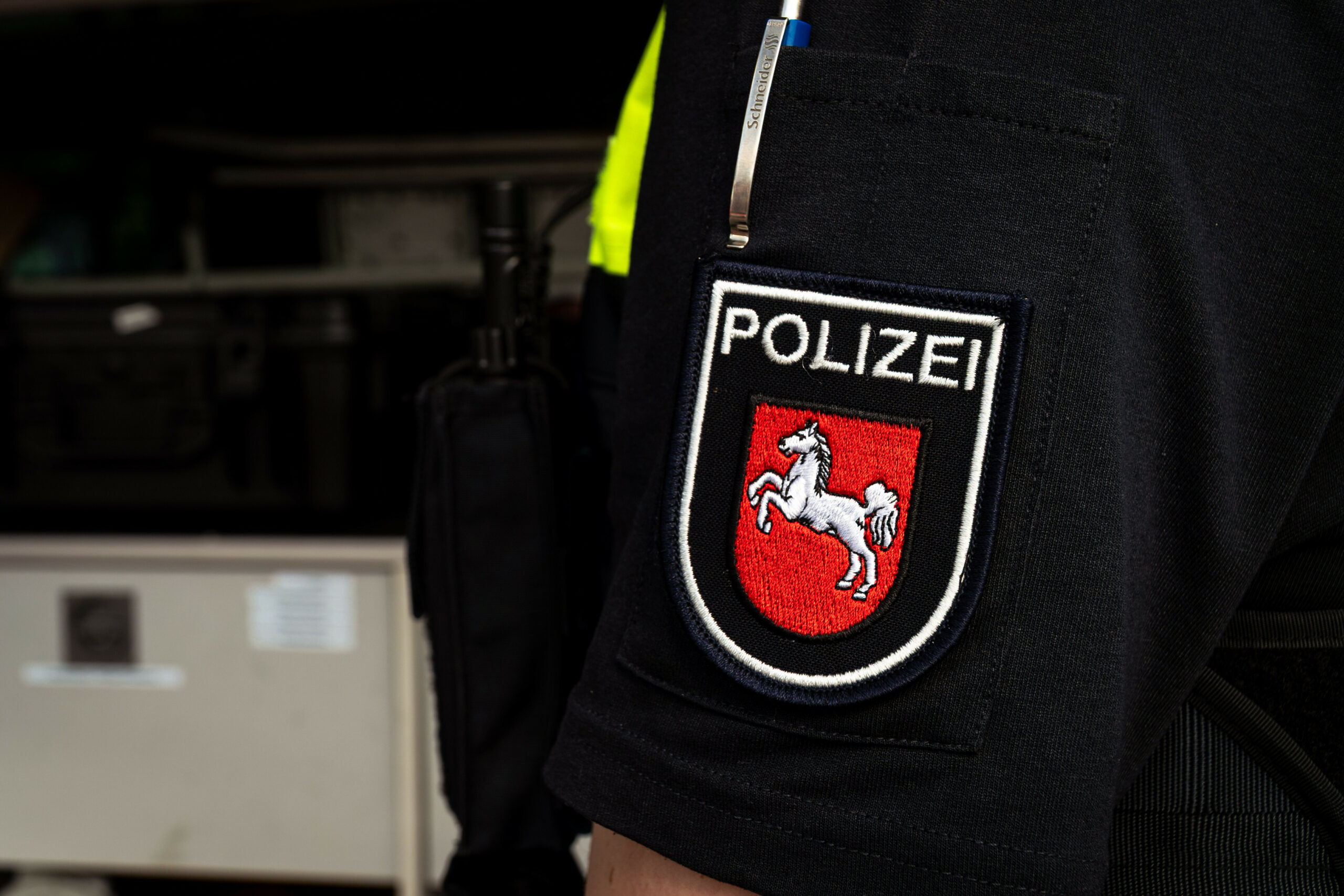 Uniformärmel eines Polizeibeamten mit dem Ärmelabzeichen der Polizei Niedersachsen. Das rote Wappen mit dem weißen Pferd ist klar erkennbar.