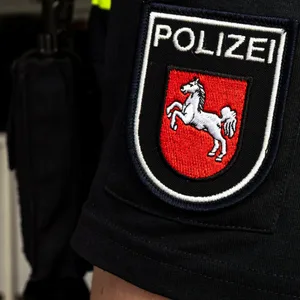 Uniformärmel eines Polizeibeamten mit dem Ärmelabzeichen der Polizei Niedersachsen. Das rote Wappen mit dem weißen Pferd ist klar erkennbar.