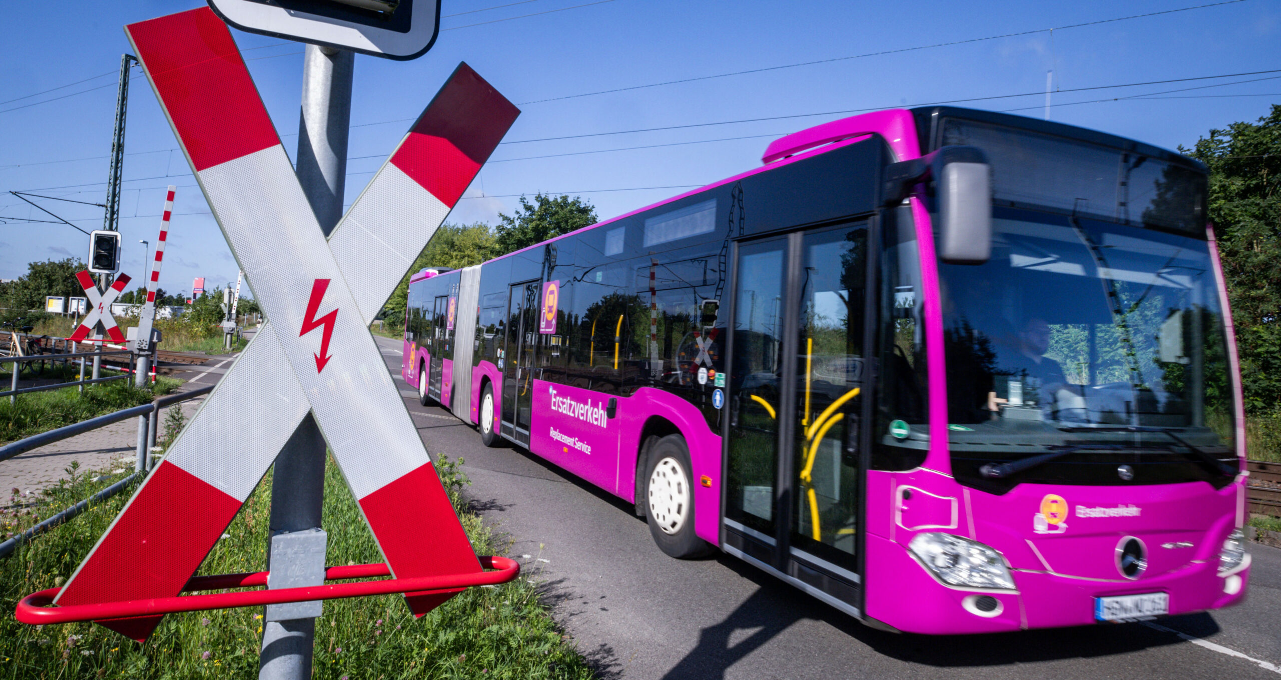 Ein Ersatzbus fährt über einen Bahnübergang.