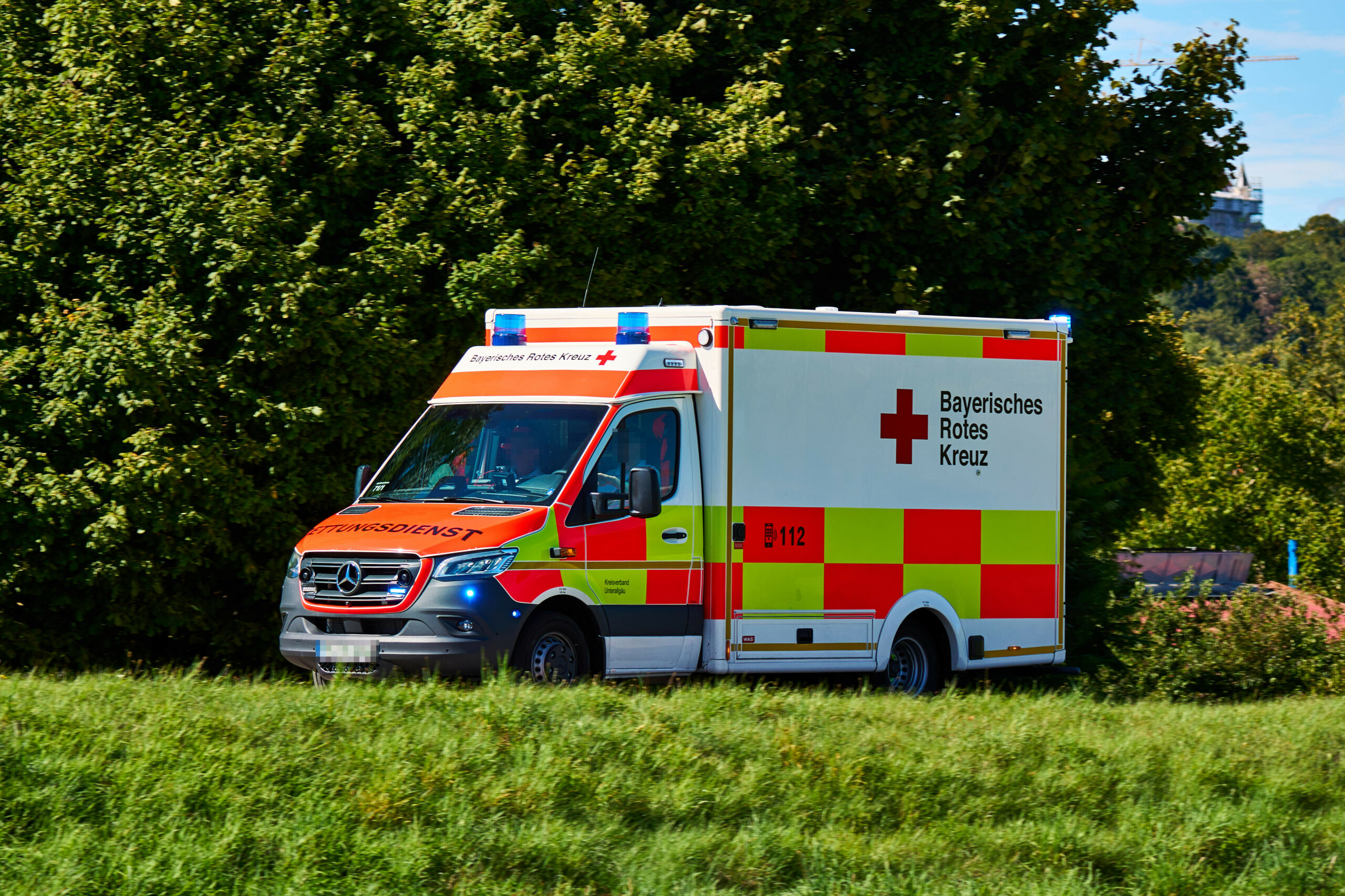 Krankenwagen des Bayerischen Roten Kreuzes mit eingeschaltetem Blaulicht im Einsatz.