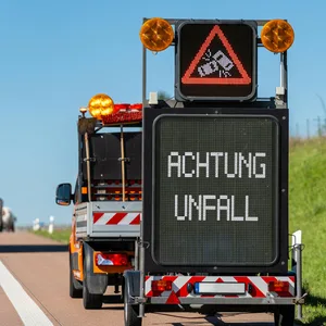 Ein elektronisches Verkehrsschild auf der Autobahn zeigt die Warnung „Achtung Unfall”.