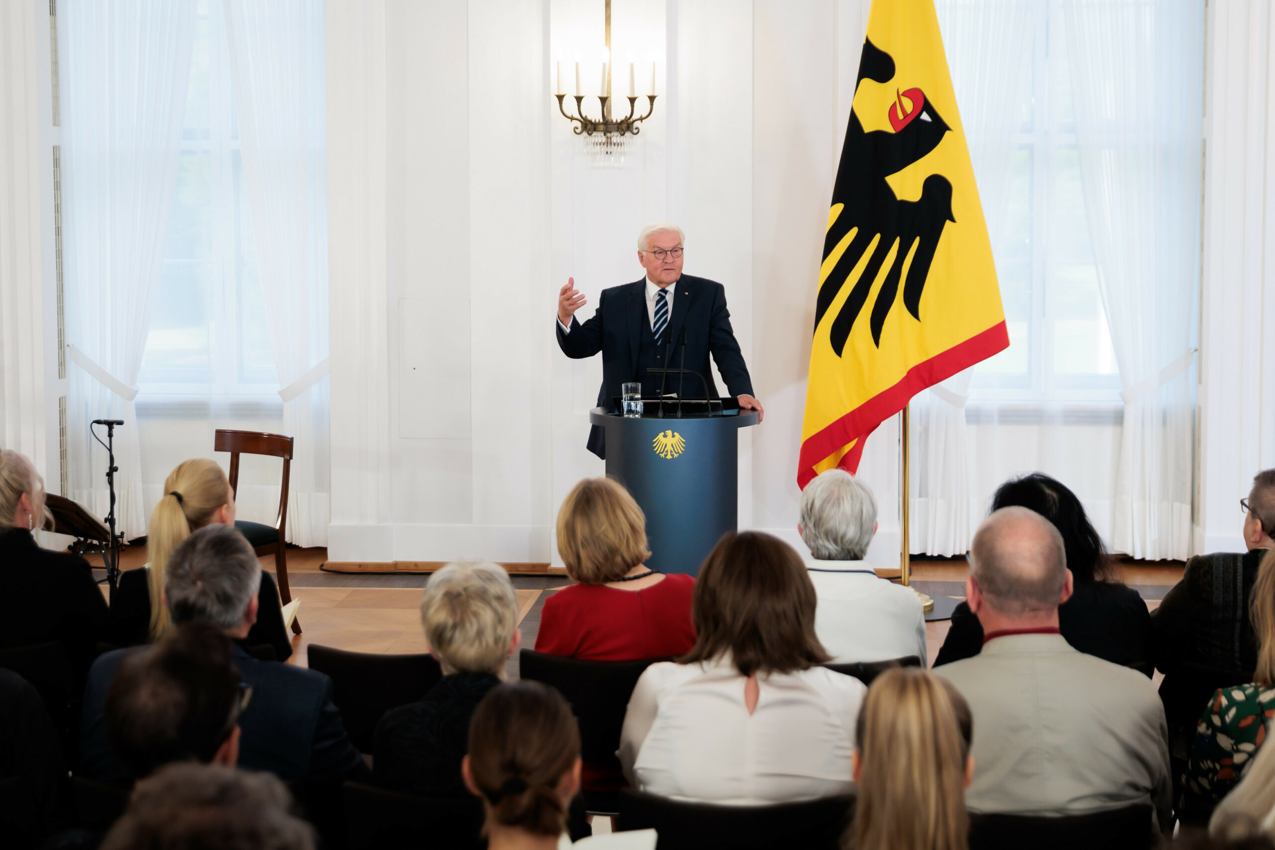 Bundespräsident Frank-Walter Steinmeier steht am Podium vor einer Bundesdienstflagge.