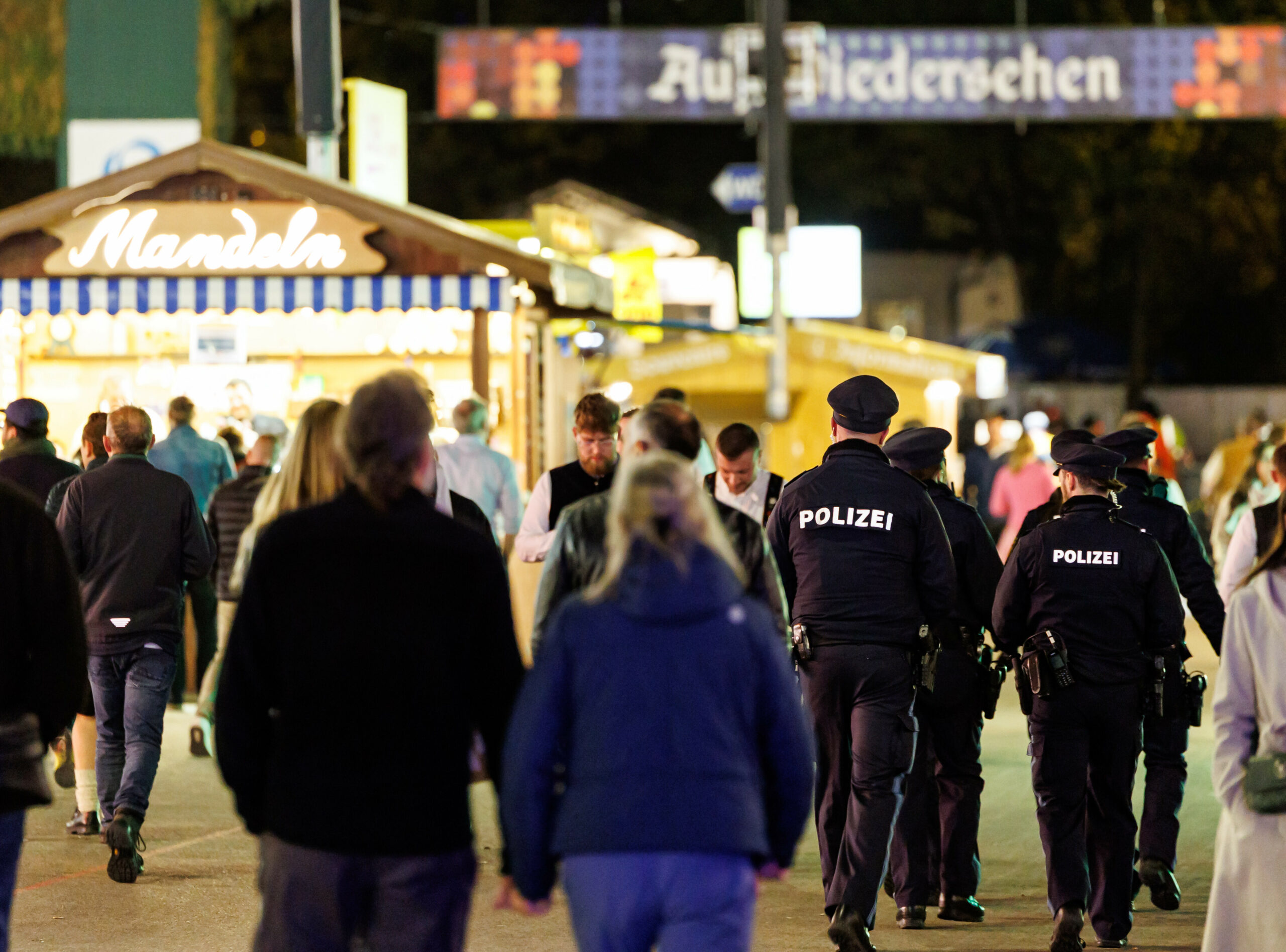Polizisten gehen über das Gelände vom Oktoberfest in München. Im Hintergrund sind Buden der Wiesn.