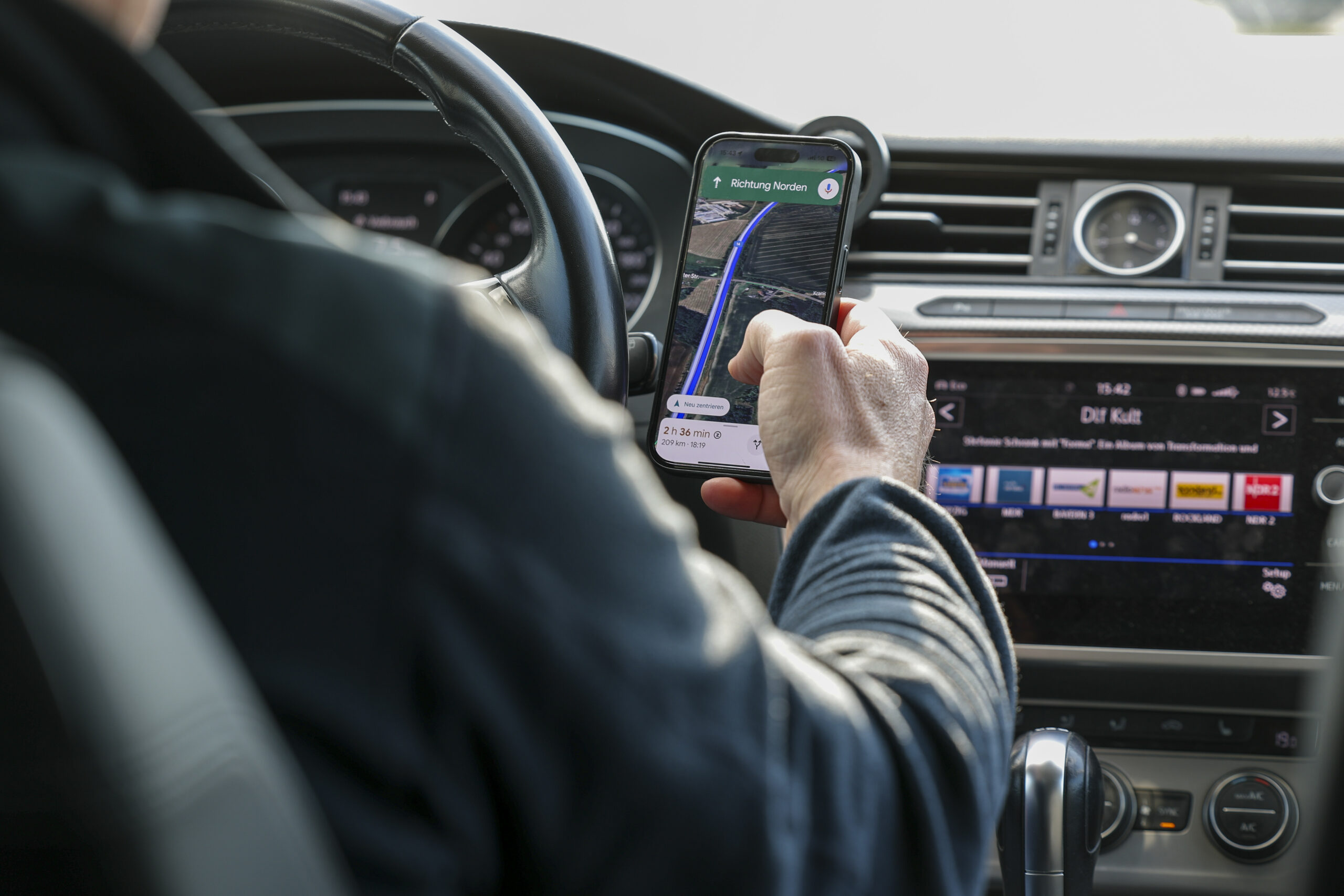 Ein Autofahrer ist mit Smartphone am Steuer.
