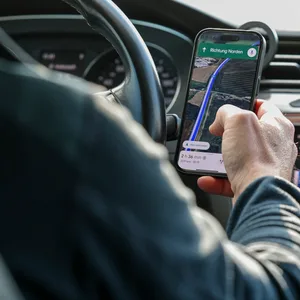 Ein Autofahrer ist mit Smartphone am Steuer.