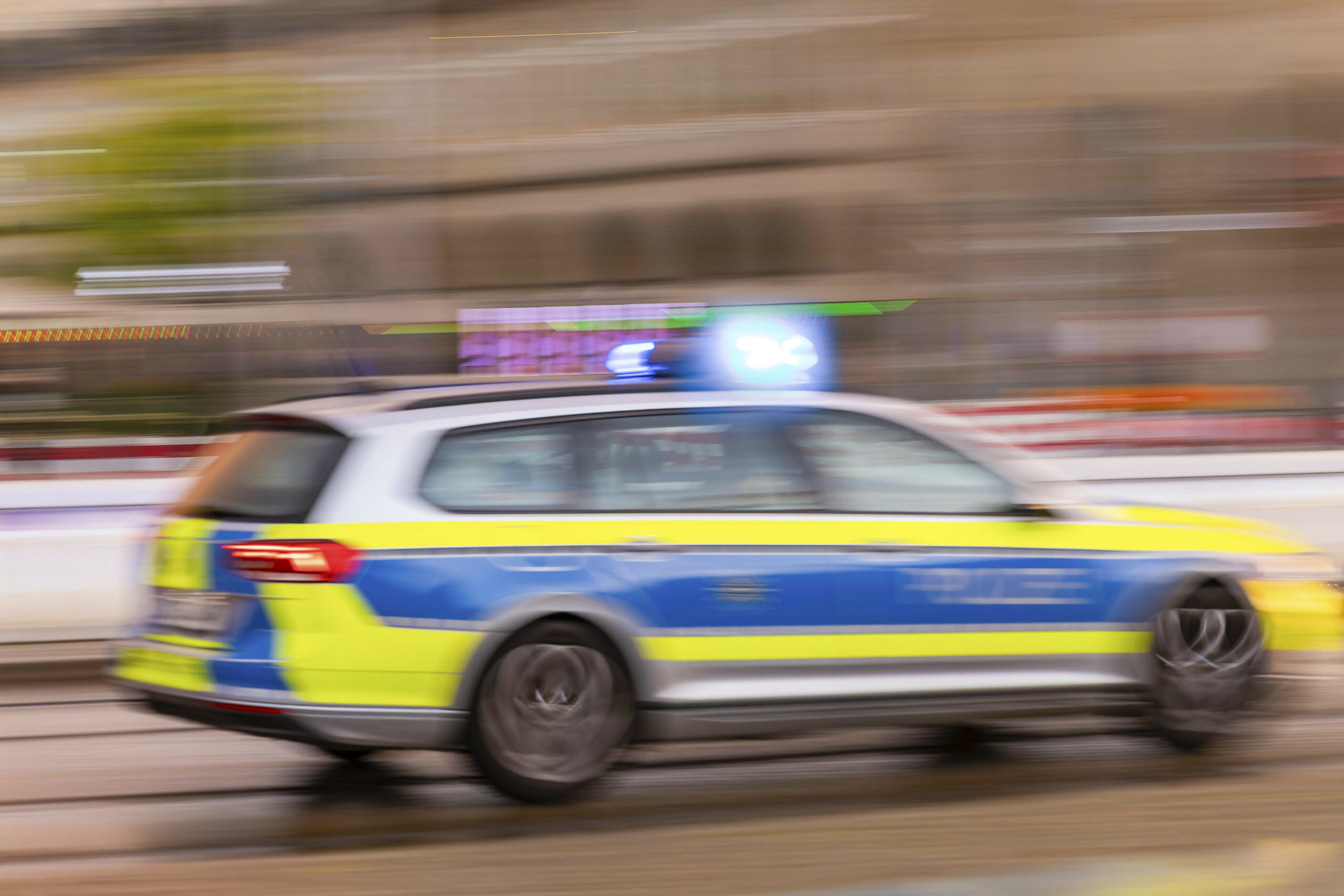 Ein Streifenwagen der Polizei fährt schnell auf der Straße. Das Bild ist unscharf.