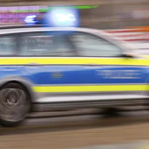 Ein Streifenwagen der Polizei fährt schnell auf der Straße. Das Bild ist unscharf.