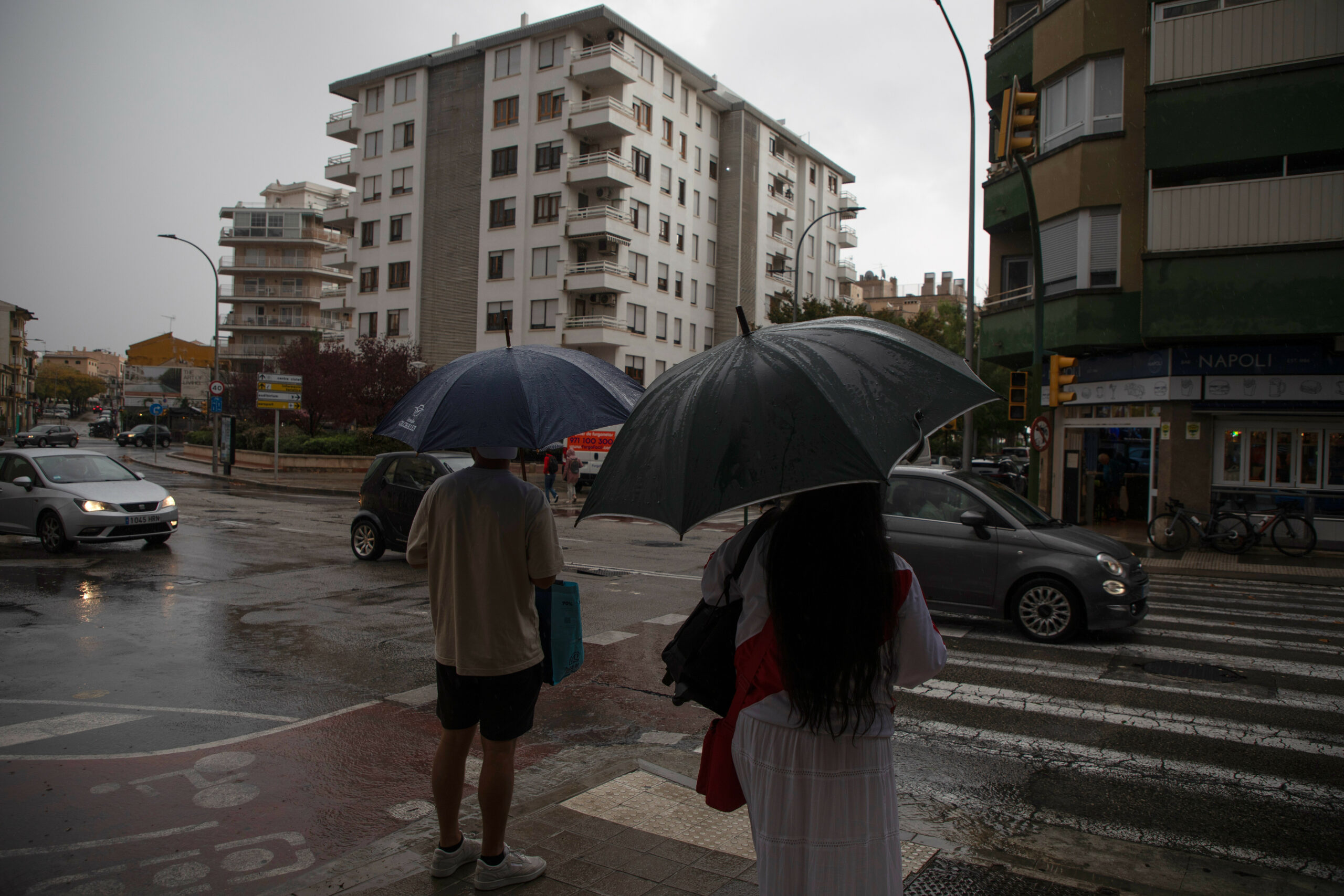 Zwei menschen stehen mit dem Rücken zur Kamera und halten jeweils einen Regenschirm.