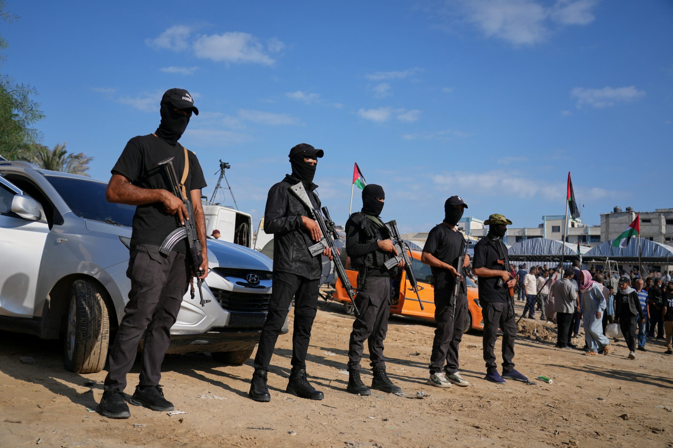 Bewaffnete Hamasanhänger stehen vor Fahrzeugen des Roten Kreuzes, die freigelassene Geiseln zur israelischen Grenze im südlichen Gazastreifen transportieren sollen.