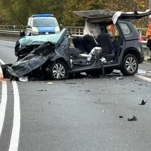 Einsatzkräfte der Feuerwehr stehen an der Unfallstelle auf der Bundesstraße 4 auf einer Brücke über den Mittellandkanal neben einem zerstörten Fahrzeug.