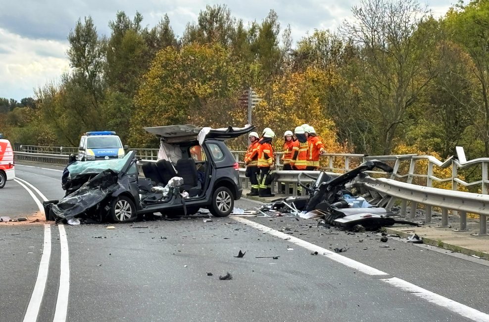 Einsatzkräfte der Feuerwehr stehen an der Unfallstelle auf der Bundesstraße 4 auf einer Brücke über den Mittellandkanal neben einem zerstörten Fahrzeug.