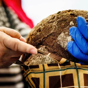 Eine Hand überreicht ein Laib Brot an eine ältere Person.