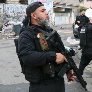 Die Polizeibeamten stehen schwarz gekleidet, mit schusssicheren Westen und bewaffnet vor den Favelas.